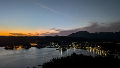 沈む夕陽と水辺の灯