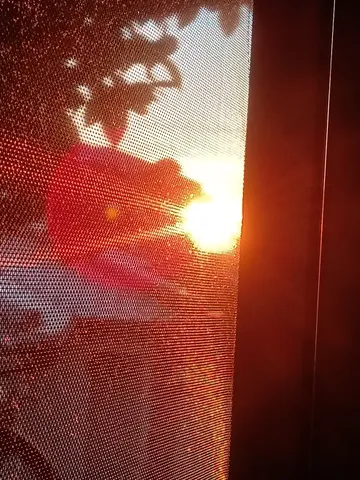 網戸越しの夕陽、茜色のレンズ効果