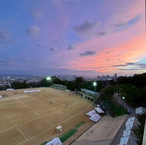 夕暮れの運動場と都市の影