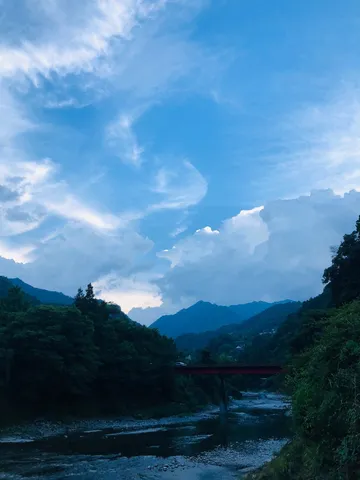 雨上がりの山間、赤橋と川