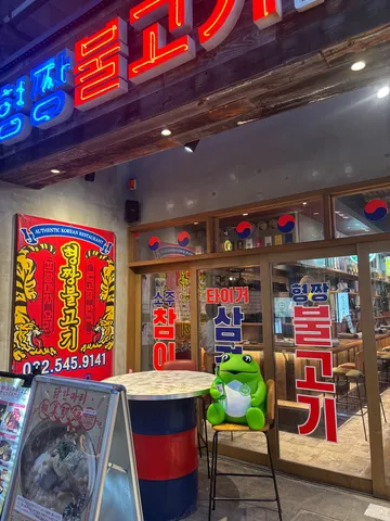 カエルの人形と韓国料理店のコントラスト