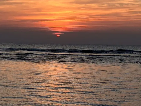 水平線に沈む太陽のオレンジグラデーション