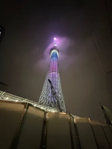 夜空に浮かぶ光の塔、雲も染まる