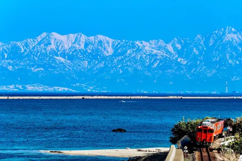 青き海と赤き列車、雪化粧の山並み