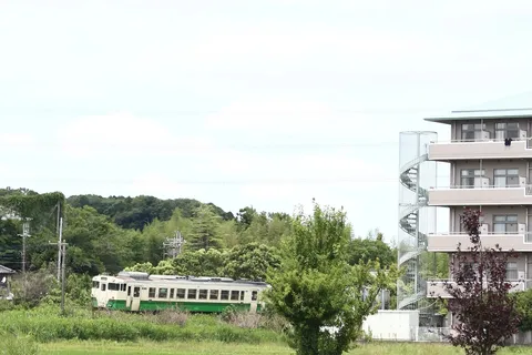 線路を走る緑の列車と螺旋階段