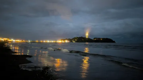 夜の灯台と波打ち際