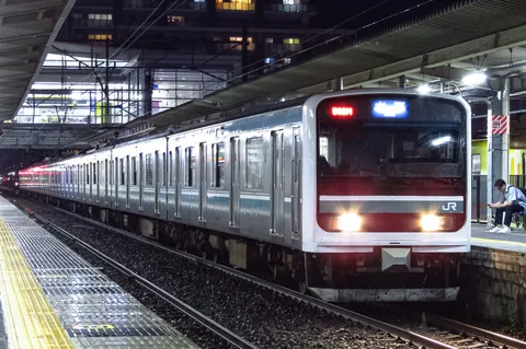 夜のホームを走る銀色電車