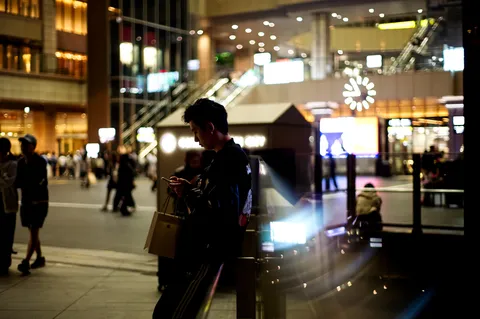 都会の夜、スマホに夢中な男性