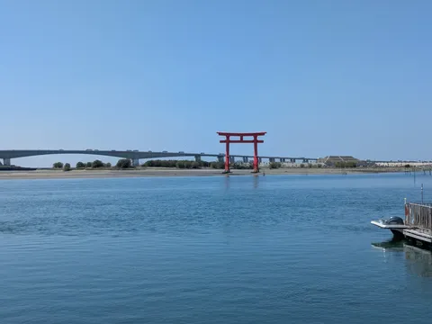 水辺に佇む赤い鳥居と遠い橋