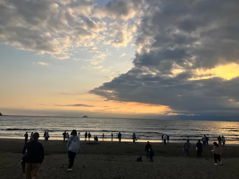 夕暮れの海岸線、潮風と人々のシルエット