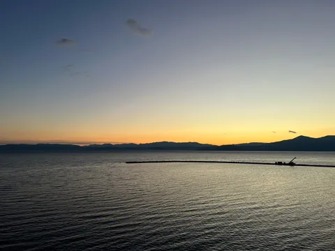 水平線に沈む夕陽と灯台