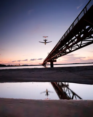 夕景の橋を横切る飛行機
