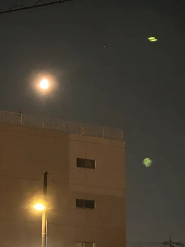 都会の夜空、月と光の交錯