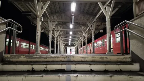 夜の無人駅、旅情を誘う赤い列車