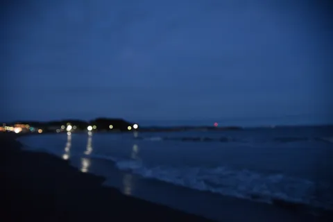 夜の浜辺に灯る光の残像