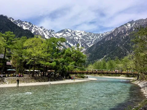 清流にかかる吊橋と雄大な峰々