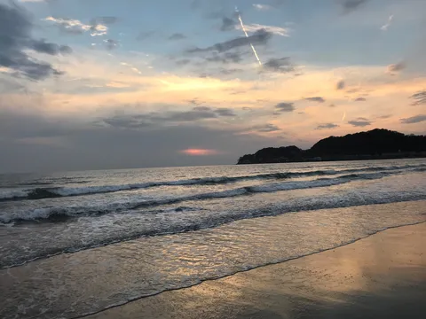 雲間から覗く夕焼けと波音