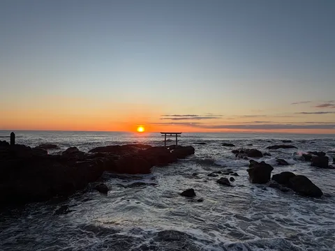 朝焼けに佇む鳥居と波