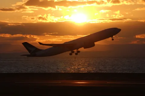 夕陽を浴びて空へ舞う飛行機