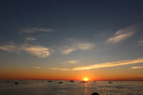 水平線に沈む夕日と遊ぶ船団