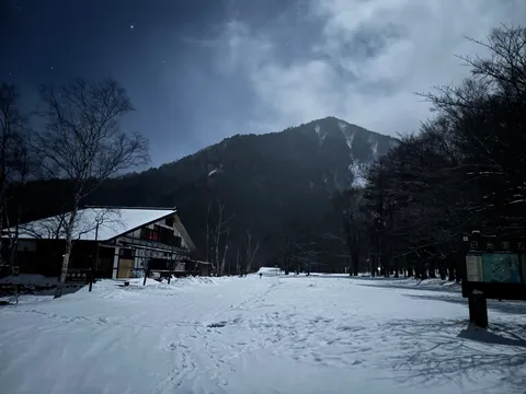 月明かりに照らされる雪山と山小屋