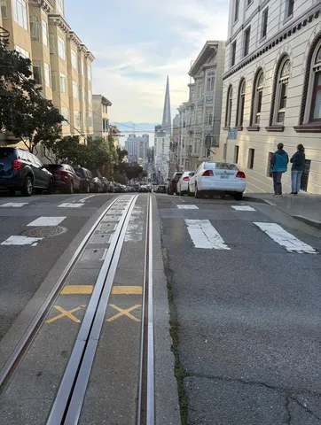 坂道の路面電車と遠くの摩天楼