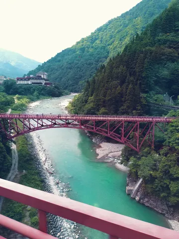 鮮やかな川と緑の渓谷、深紅の橋