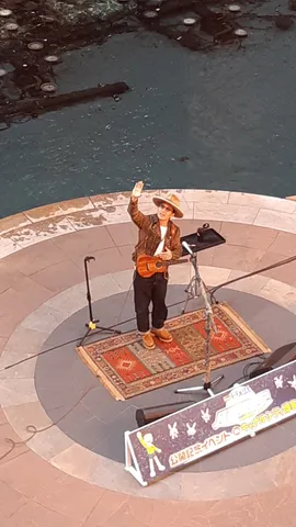 ウクレレ奏者、水辺のステージで歌う