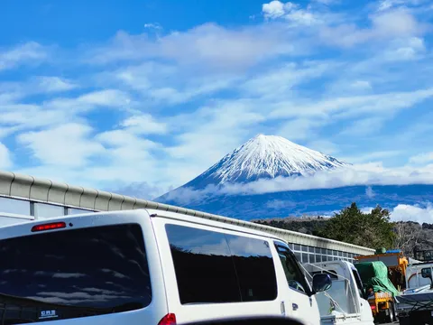 雲間にそびえる富士山と車列