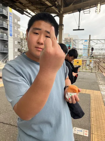 駅のホームで、おにぎりと中指