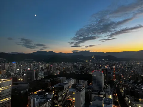 夕暮れに浮かぶ三日月と街の灯