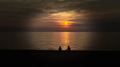 夕暮れ、水辺に佇む二人
