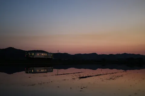 夕暮れに映る、列車と水面の幻想