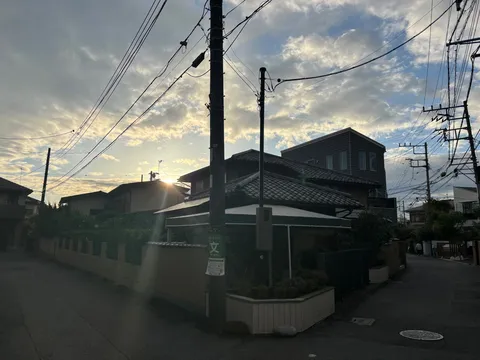 夕暮れの瓦屋根と電線路地