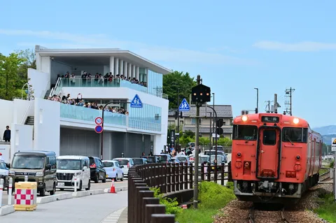 オレンジ色の列車を見守る人々