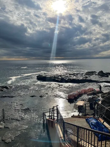雲間から差し込む光と波打ち際
