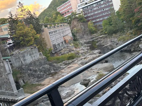 夕暮れの川辺と鉄柵の影
