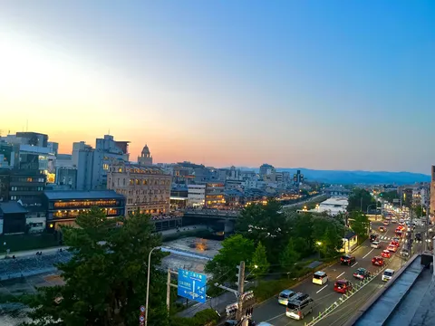 夕暮れの川辺に灯る街