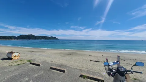 国道沿いの海辺、錆びたドラム缶と原付