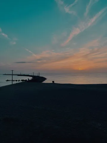 夕暮れの海辺、灯台へ続く道