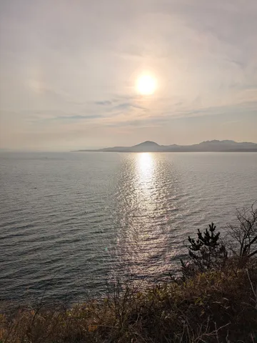 水面に映る太陽と、遠くの山並み