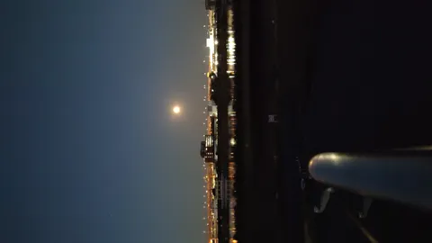 水面に映る夜景と明るい月