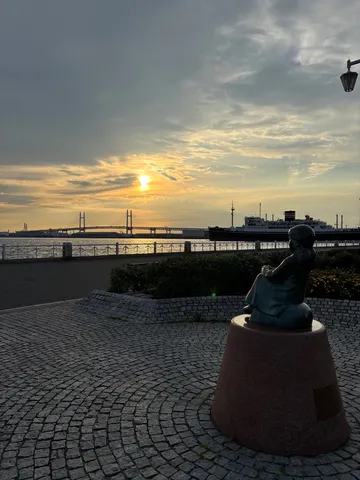夕暮れの港、少女が見つめる先