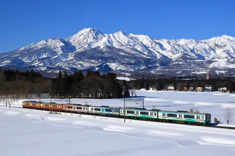 白銀を彩る、連なる列車と雪山