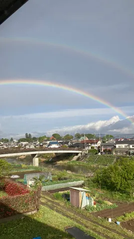 虹が架かる、水田と町並み