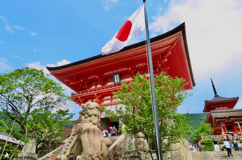 青空に映える朱色の寺院と日の丸
