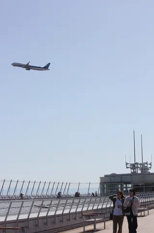 大空へ伸びる飛行機と見守る眼差し