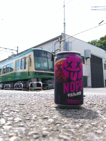 電車を背景に佇むNOPE缶