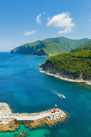 紺碧の海を駆ける船と赤い灯台