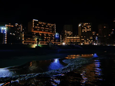 夜の浜辺に映る灯りの影